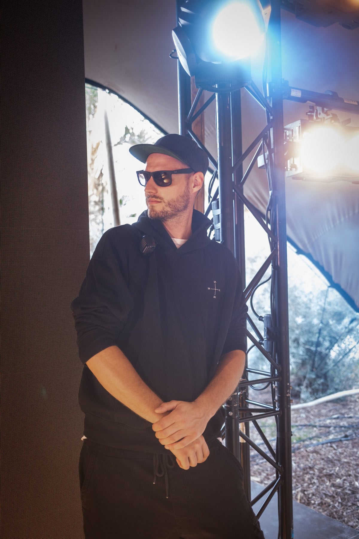 Crew-Mitglied im schwarzen SL/SR Hoodie lehnt an der Traverse